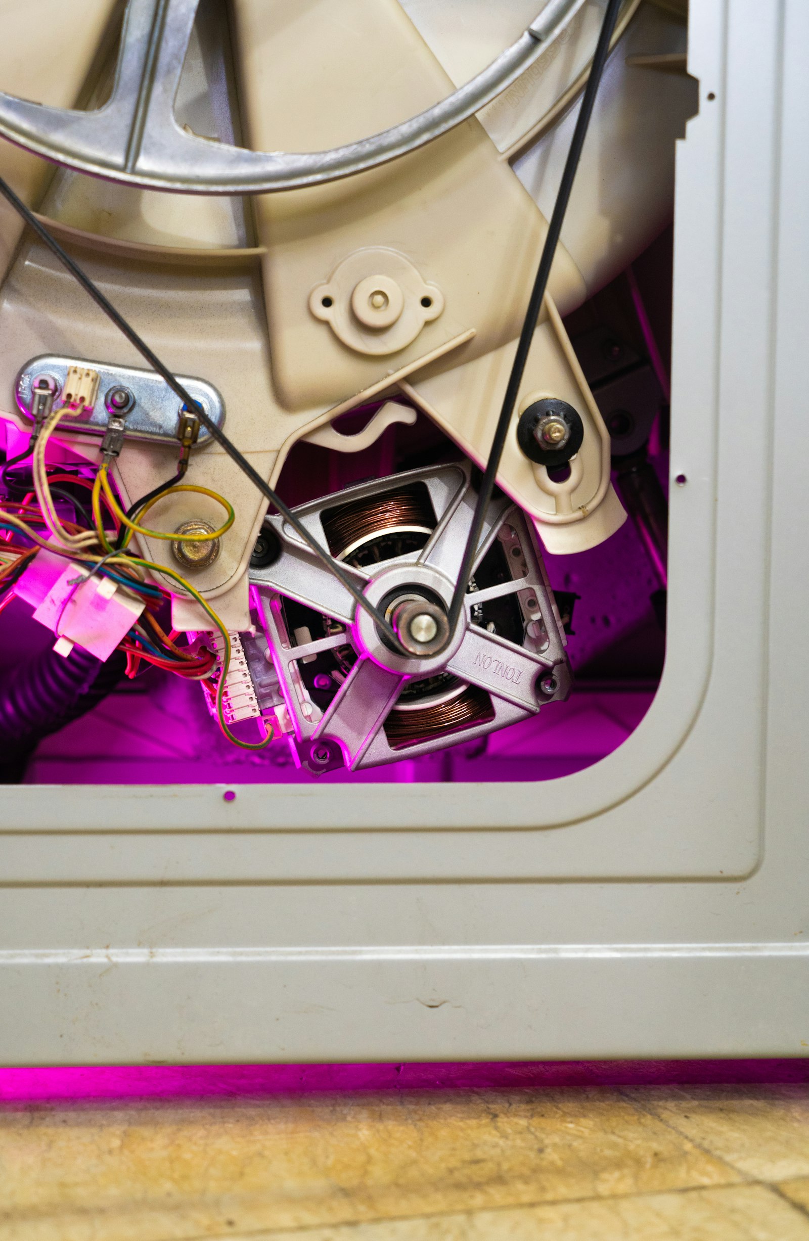 Vue rapprochée du moteur et de la courroie d'un lave-linge démonté pour réparation